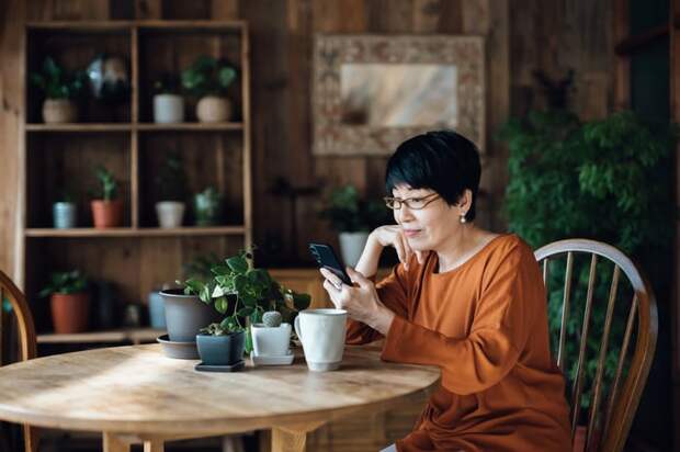 Person sitting at a table looking at a phone.