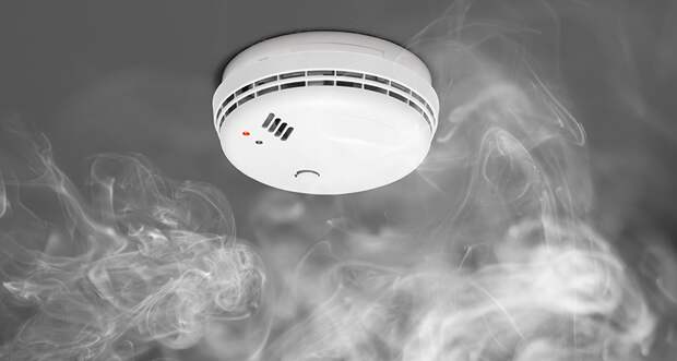 an image of a smoke detector on the ceiling and smoke wafting below it