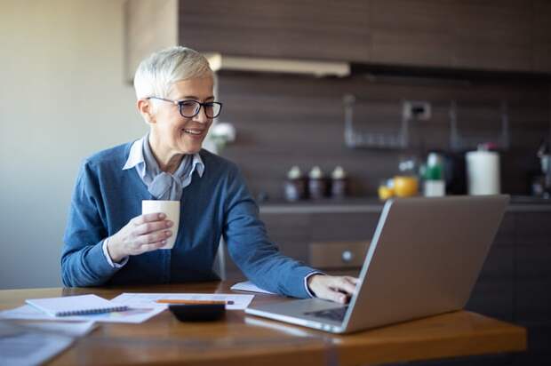 Person in kitchen, looking at laptop.