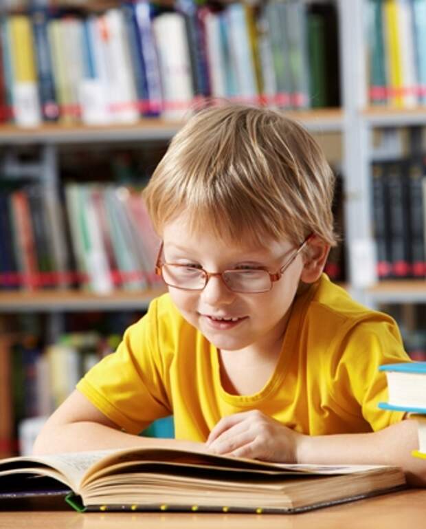 маленький мальчик читает книгу в библиотеке (фотография) - - PressFoto