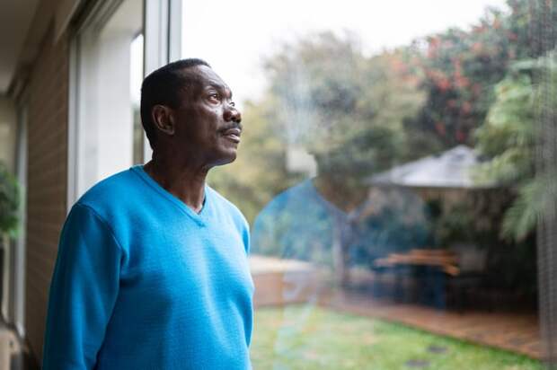 Person with a serious expression looking out a window.