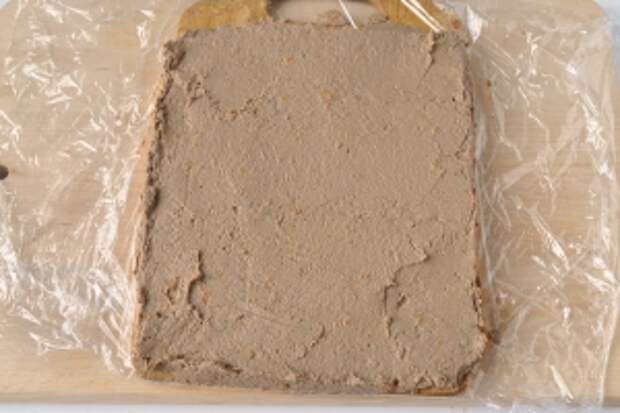 Доску застелить пищевой плёнкой, и ровным слоем выложить печень. Поместить в морозильник на 7-12 минут, что бы слой схватился и не продавливался начинкой.