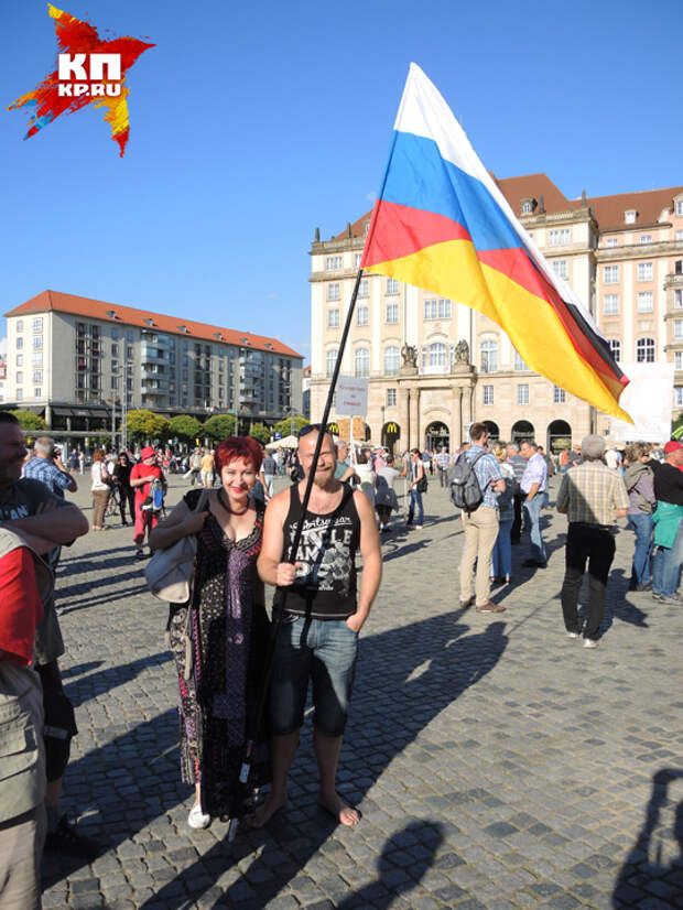Дарья и немец держат флаг, наполовину немецкий, наполовину русский.