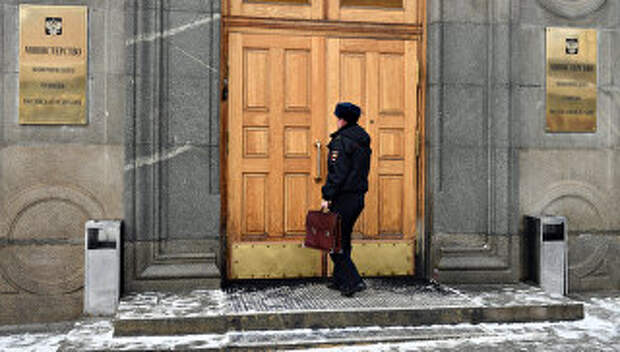 Сотрудник полиции входит в здание министерства экономического развития Российской Федерации