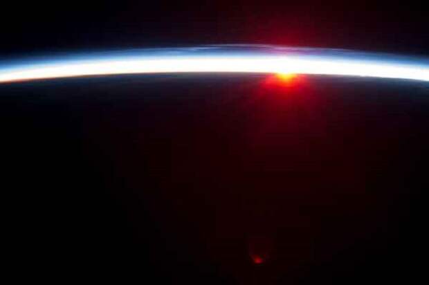 Тонкая линия земной атмосферы и заходящее Солнце.