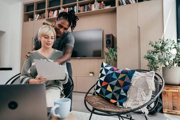 Couple having discussion while using laptop and looking at documents.