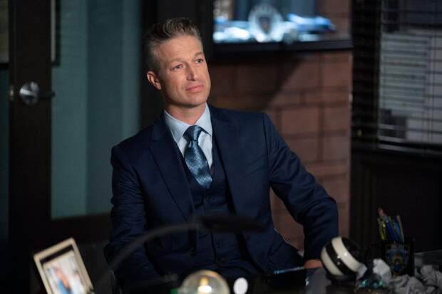 Carisi sitting in front of Benson's desk with his hands on his hips on Law & Order: SVU Season 26 Episode 2