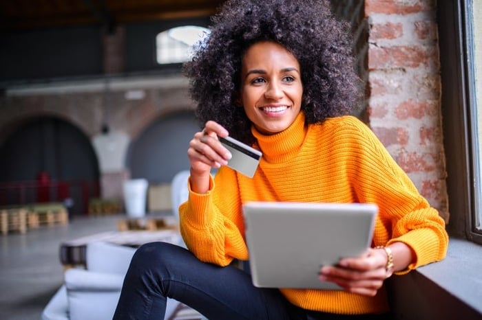 African American woman happily uses her credit card to make an online purchase.