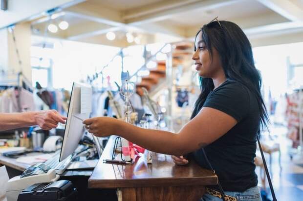 A young adult pays for a shopping purchase with a credit card.