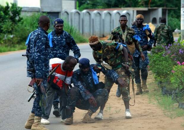 Rebel soldiers of Ivory Coast opposition leader Alassane Ouattara help their wounded comrade during a clash with Ivorian forces at Golf hotel in Abidjan