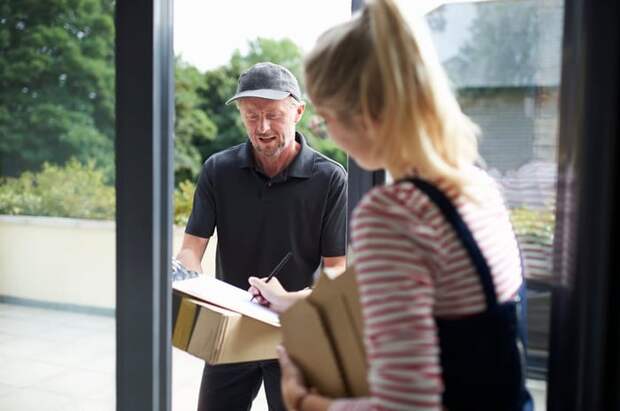 Woman signing for packages with a delivery person.