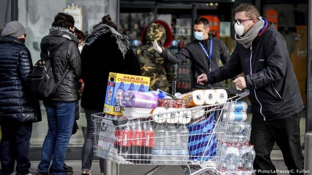 Мужчина с полной тележкой туалетной бумаги, бытовой химии и напитков - закупка из-за коронавируса