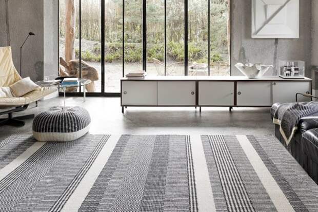 эффектное дополнение интерьера гостиной в серых тонах ковром на полу 