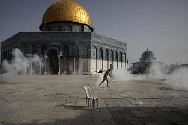 Палестинец убегает от слезоточивого газа во время столкновений с израильскими силами безопасности перед мечетью Купол Скалы в комплексе мечети Аль-Акса в понедельник