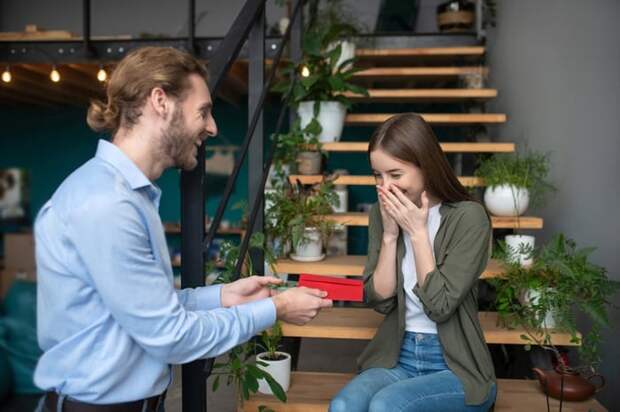 Man hands young girl a gift in an envelope.