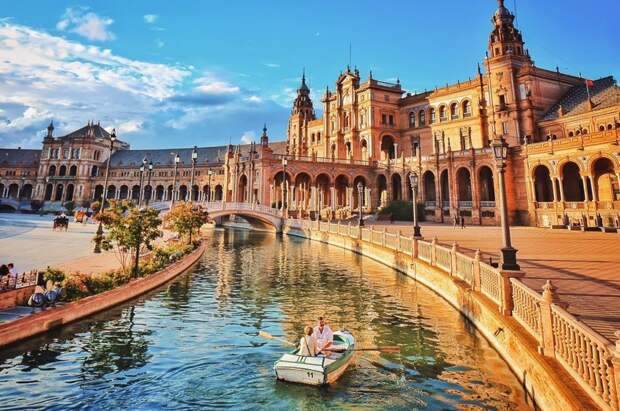 Этот снимок показывает площадь Испании в Севилье, купающуюся в теплом свете в комплекте с романтической поездкой на лодке. разница, фотографии
