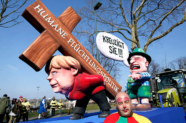 A carnival float with papier-mache caricatures mocking Bavarian Governor Horst Seehofer and German Chancellor Angela Merkel is displayed at a postponed "Rosenmontag" (Rose Monday) parade, at one location in Duesseldorf, Germany, March 13, 2016, after the original parade in February was cancelled due to severe weather. Words read 'crucify her' 'human politics for migrants'. REUTERS/Ina Fassbender