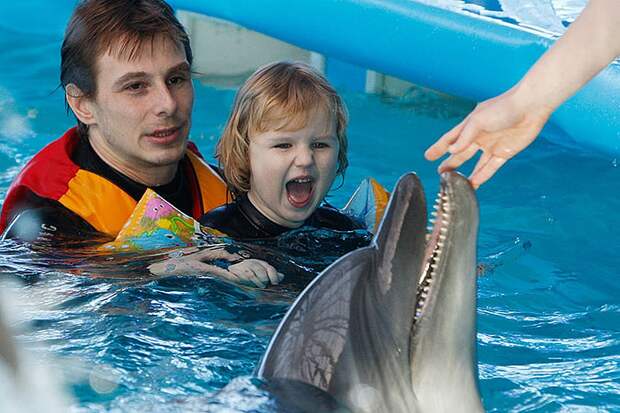 Сеанс дельфинотерапии для маленькой пациентки. Фото: РИА Новости