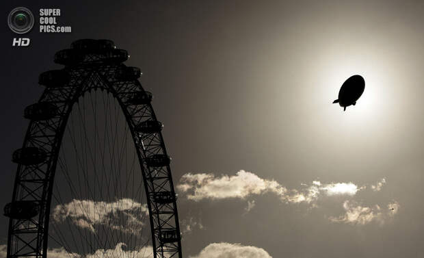 Великобритания. Лондон. 9 ноября 2006 года. Дирижабль, рекламирующий курорт в Дубаи, проплывает мимо Лондонского глаза. (Peter Macdiarmid/Getty Images)