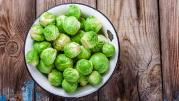 Fresh organic Brussels sprouts in a bowl on a wooden table