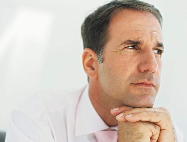 A man with his hands under his chin staring off to the side.
