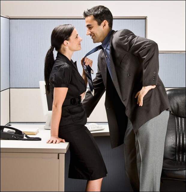 Co-workers kissing in office cubicle