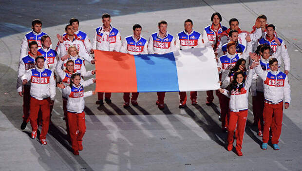 Российские медалисты выносят российский флаг во время церемонии закрытия XXII зимних Олимпийских игр в Сочи