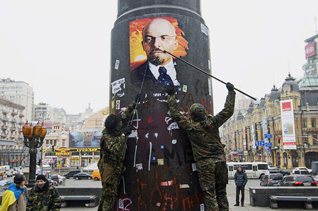 Украинские националисты сдирают портрет Ленина, приклеенный сторонниками Коммунистической партии к постаменту его памятника, разрушенного накануне