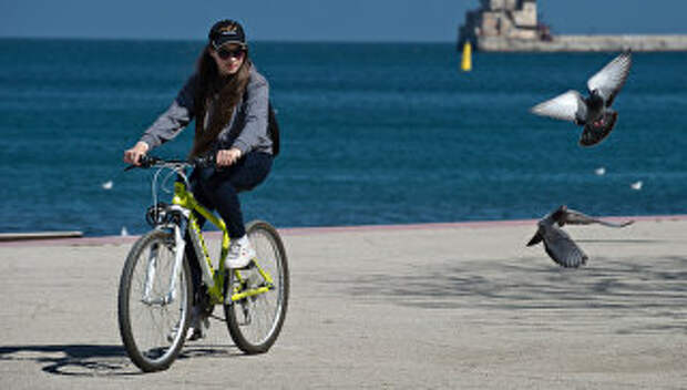 Девушка на велосипеде на набережной Феодосии