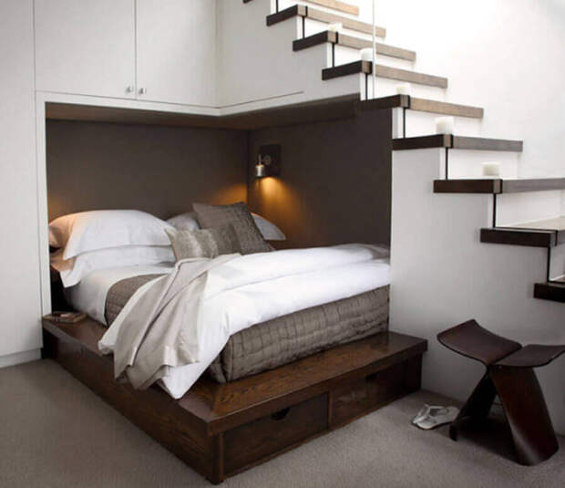 Для экономии пространства можно обустроить спальное место прямо под лестницей.
