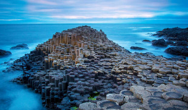 Causeway Coastal Route Северная Ирландия Тысячи шестиугольных базальтовых колонн считаются мостовой троллей, прошедших здесь от гнева Одина и других богов. На самом же деле, эти причудливые скальные образования — результат извержения вулкана.