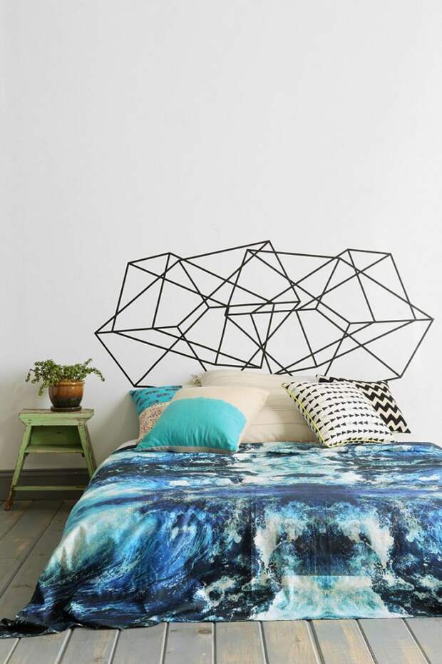 Просторная светлая спальня с необычным геометрическим рисунком над изголовьем кровати и ярким акцентом на постельном белье с морскими мотивами