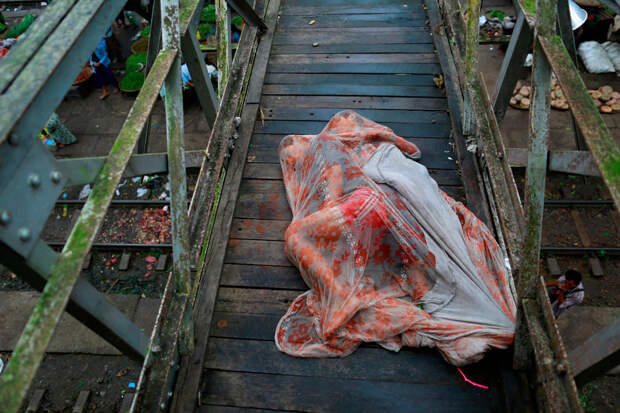Спящие под москитной сеткой на мосту над железнодорожной станцией около Янгона, Мьянмы