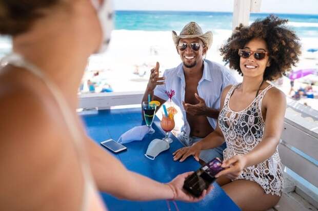 A happy couple on vacation pay for their meal with their travel rewards credit card.