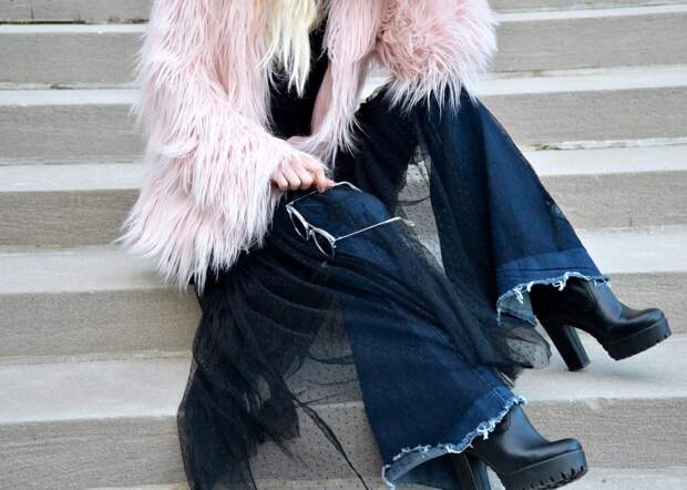 Woman sitting in a black mesh dress and faux fur coat