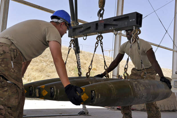 BAGRAM AIRFIELD, Afghanistan -- U.S. Air Force Tech. Sgt. Matthew Garrett (left) and Staff Sgt. Terrin Love guide GBU-38s as they are hoisted during a bomb build here Aug. 14, 2014. Both are Air National Guardsmen from the 187 Fighter Wing and natives of