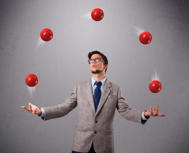 young man standing and juggling with red balls