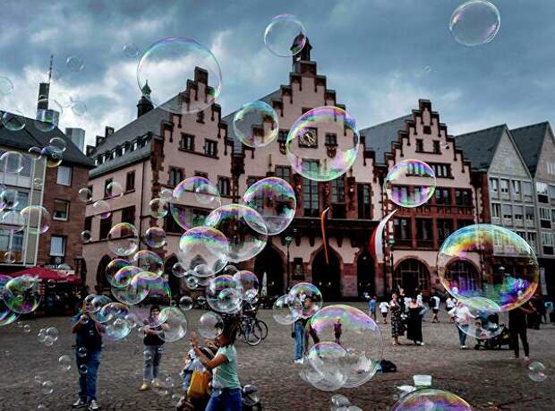 Уличный артист пускает мыльные пузыри перед зданием ратуши во Франкфурте, Германия