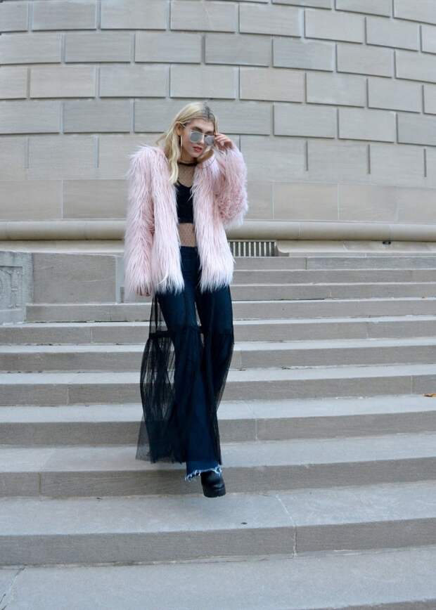 Street Style star in mesh black dress, faux fur jacket, and touching her sunglasses